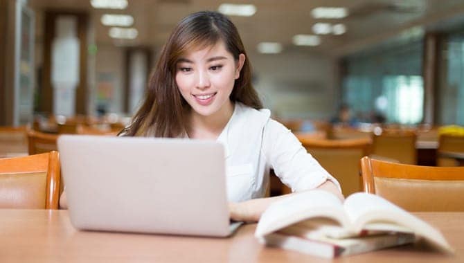 Asian beautiful female student study in library with laptop