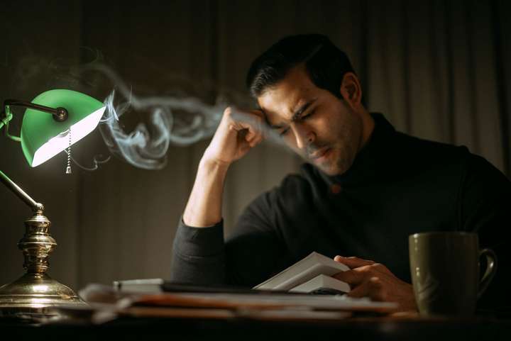 man reading a book with cup of tea