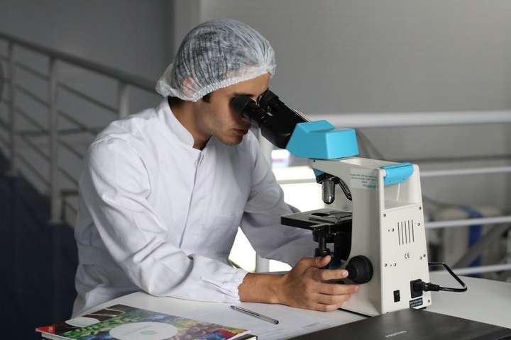 man looks through microscope